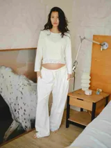 Conjunto de pijama blanco de algodón, compuesto por una remera de manga larga con detalle de encaje en el ruedo y un pantalón largo de corte holgado con cintura elástica ajustable.