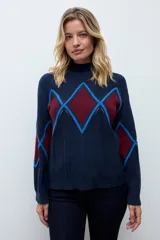 Media polera de tejido de punto color crudo, con diseño de rombos en el frente en tonos gris y negro. Presenta cuello alto y mangas largas.