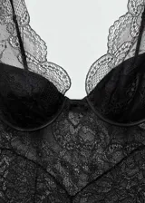 Vestido midi entallado de encaje y guipur negro, con escote en pico, tirantes anchos y sujetador incorporado. Presenta terminaciones festoneadas y diseño semitransparente.