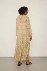 Vestido largo con estampado abstracto en tonos beige y marrón, de mangas largas con puños elásticos, escote en V con volantes y falda evasé con recortes. Incluye cinturón fino negro.