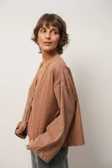 Blusa marrón de corte crop, escote en V y mangas largas anchas. Cierre frontal con lazos.