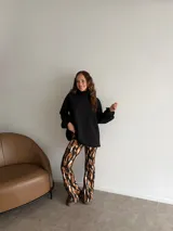 Pantalón tipo oxford de tiro alto, con estampado abstracto en tonos tierra, negro y crema. Presenta un corte ajustado en la parte superior y acampanado desde la rodilla hacia abajo.
