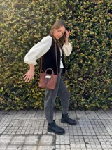 Chaleco de cuero negro con tachas metálicas doradas en los bordes frontales.