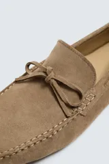 Mocasín casual fabricado en piel con acabado serraje, con detalle de lazo en el empeine y horma redonda.