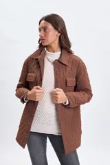 Sobrecamisa de diseño capitoneado en color marrón, con cuello clásico, cierre frontal mediante botones a presión y bolsillos frontales con solapa.