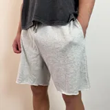 Short de algodón gris melange con cintura elástica y cordón de ajuste, de corte holgado y ruedo sin costura.