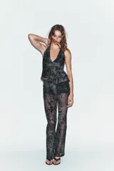 Top de cuello halter con lazada al cuello, escote en pico y bajo asimétrico. Confeccionado en tul con diseño de flores flocadas en contraste.