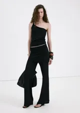 Pantalón de punto fino color negro, de diseño recto y tiro medio, con falda corta superpuesta integrada.