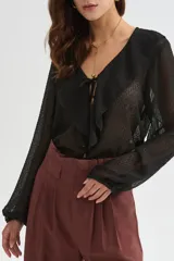 Blusa blanca de poliéster con cuello en V, volados frontales y mangas largas con elástico en los puños.