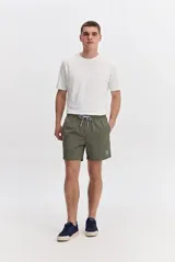 Short de baño verde militar de textura sutil, con cintura elástica ajustable mediante cordón bicolor y bolsillos laterales.