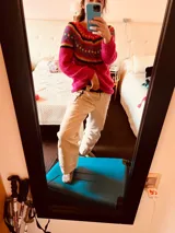 Sweater tejido a mano en lana de color fucsia con diseño geométrico multicolor.