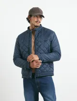 Campera capitoneada de color azul oscuro, con cierre frontal de metal y botones a presión. Presenta bolsillos laterales y en el pecho con cierres metálicos.