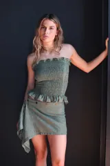 Falda corta de corte asimétrico en color marrón con efecto jaspeado. Presenta un diseño envolvente con cierre lateral de botones y detalle de fruncido, confeccionada en tejido ligero.