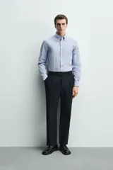 Camisa regular fit de algodón con diseño de rayas finas celestes y blancas. Cuenta con cuello abotonado, manga larga con puños abotonados y cierre frontal de botones.