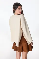 Sweater de tejido de punto color crudo, con cuello redondo, corte holgado y mangas largas con terminación acampanada.
