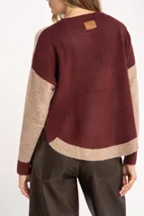 Sweater de punto con diseño color block en tonos beige, marrón y bordó, de cuello redondo y manga larga con puños acanalados en contraste.
