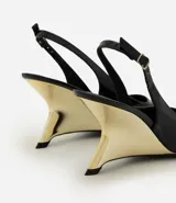 Zapato slingback de punta fina en material sintético efecto charol negro, con tacón anabela de diseño arquitectónico en acabado dorado cromado y tira trasera ajustable con hebilla.