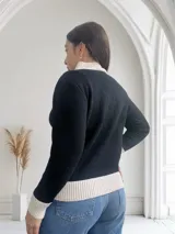 Sweater negro de punto con cuello alto y ribete color crema en cuello, puños y ruedo. Presenta un bordado de siluetas de gatos en color crema en el frente.