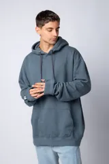 Buzo canguro oversize de tela friza, color negro, con capucha, cordones ajustables con logo y bolsillo frontal tipo canguro.