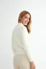 Buzo de punto color crema con cuello alto, manga larga y puños y ruedo acanalados.