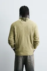 Polo de punto con diseño desagujado, color verde, de corte relajado, manga larga y cuello solapa con cierre frontal de tres botones. Presenta puños y ruedo con acabado en rib.