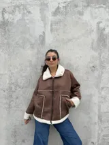 Campera tipo gamulán color marrón, con interior y detalles en corderito blanco. Presenta cierre frontal, cuello solapa y bolsillos laterales.