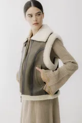 Chaleco de piel sintética en color chocolate, con cierre frontal y detalles de cuero en los bordes. Presenta un diseño de cuello solapa y ajuste lateral con hebillas.