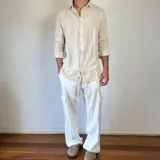 Camisa de lino con corte oversize, cuello clásico y cierre frontal con botones. Presenta mangas largas con puños arremangados y una textura rústica característica del tejido.
