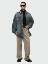 Camisa de denim Balmain de corte oversize y lavado desgastado, con cierre frontal de broches metálicos, cuello clásico y dos bolsillos con solapa en el pecho.