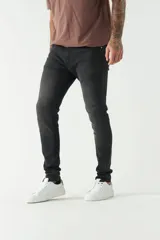Jean skinny de hombre, color gris oscuro con efecto desgastado. Presenta cinco bolsillos, pasacinto y logo bordado.