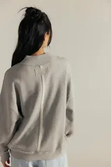Sweater de punto color gris, con cuello redondo alto y mangas largas abullonadas con puños ajustados, de diseño holgado.
