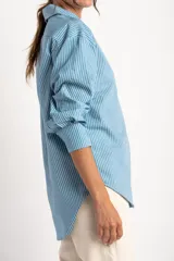 Camisa celeste con rayas verticales blancas, de corte oversize y manga larga.