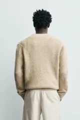 Sweater de punto color beige, de corte relajado, con cuello redondo y diseño texturizado en estructura waffle.