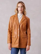 Blazer de eco cuero marca Baccini, con cuello de solapa, cierre frontal con botones y bolsillos delanteros aplicados. Presenta un corte oversize y forro interno a tono.