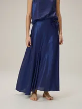 Falda larga azul marino de tejido satinado, con detalle de aplique floral en la cintura.