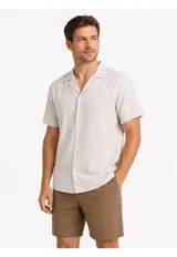Camisa de manga corta color beige, confeccionada en mezcla de lino y algodón, con cuello camisero abierto y cierre frontal de botones.