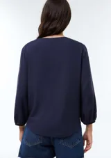 Blusa de viscosa color marrón con escote en V, mangas tres cuartos con puños elásticos y corte holgado.