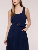 Vestido midi blanco de la marca Nina Leonard, sin mangas y con escote cuadrado. Cuenta con corte en la cintura, bolsillos laterales con solapa, falda fluida con detalle de frunce inferior e incluye un cinturón del mismo género con hebilla carey.