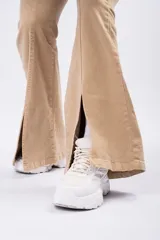Pantalón tipo oxford de tiro alto en color beige, confeccionado en gabardina. Presenta una línea frontal marcada y tajos en el ruedo de ambas piernas.