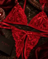 Conjunto de lencería rojo de encaje con diseño de aperturas, tiras regulables y detalles de moños satinados.