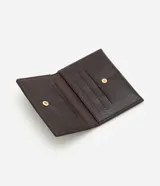 Billetera pequeña tipo sobre, color marrón oscuro con textura efecto cocodrilo. Cuenta con cierre mediante botón metálico y compartimentos internos organizados para tarjetas.