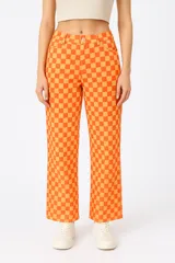 Pantalón de tiro medio, corte recto y holgado, con estampado de damero en tonos naranja y ocre.