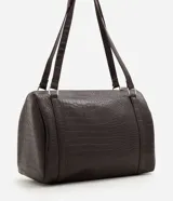 Cartera bowling grande Satinato de formato cilíndrico, confeccionada en PU con textura croco y herrajes metálicos plateados.