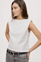 Remera sin mangas negra con cuello redondo y hombros estructurados con hombreras, de corte recto y largo a la cintura.