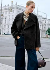 Abrigo corto de corte oversize confeccionado en mezcla de lana, con cuello de solapas con muesca, cierre frontal de doble botonadura y dos bolsillos de ribete laterales.