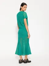 Pollera midi azul marino, ajustada al cuerpo hasta las rodillas y con terminación acampanada. Tejido calado con diseño floral.