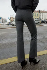 Leggings de tiro alto color gris oscuro, con cintura elástica, falsos bolsillos de vivo en la espalda y pernera larga acabada en evasé. Cierre frontal con cremallera, botón interior y gancho.