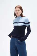 Polera de punto acanalado con diseño bicolor en blanco y negro, cuello alto con cierre frontal y manga larga.
