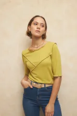 Remera color verde claro de manga tres cuartos, escote redondo y detalle de costuras superpuestas de forma asimétrica.