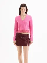 Cardigan de punto color rosado, con escote en V, mangas largas y cierre frontal con tres botones. Cuenta con detalle de godets en el bajo, aportando movimiento.